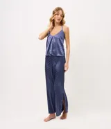 Pijama largo de satén azul con estampa de lunares, compuesto por una musculosa de escote en U con breteles finos y un pantalón de pierna recta con cintura elastizada.