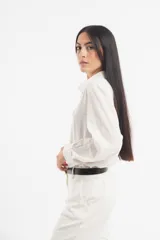 Camisa color beige de corte clásico, con cuello camisero, mangas largas con puños abotonados y cierre frontal con botones.