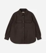 Camisa de corte largo tipo shacket, confeccionada en polivelour color marrón. Presenta cuello camisero, cierre frontal con botones, hombros caídos, mangas largas y dos bolsillos frontales aplicados con solapa.