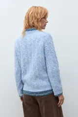 Sweater de punto con diseño de trenzas verticales, color rosa melange, de cuello redondo y manga larga con puños acanalados.