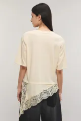 Remera negra de corte oversize, con escote redondo, mangas cortas y detalle de tajo irregular con terminación en puntilla en el ruedo. Confeccionada en jersey de algodón.