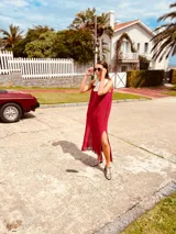 Vestido de fiesta fucsia con escote y espalda de cuero, tajos laterales con hilo metálico y terminación con flecos.