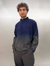 Camisa de lana color gris con cuello mao, corte recto y mangas largas con detalle texturizado. Presenta cierre invisible en el escote superior y tajos laterales.