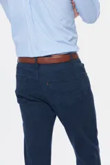 Pantalón de vestir azul marino, de corte recto, con bolsillos laterales y traseros. Se ajusta a la cintura con cinturón de cuero marrón.