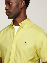 Camisa amarilla de manga corta con cuello abotonado y logo de Tommy Hilfiger bordado en el pecho.