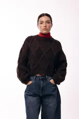 Sweater de tejido de punto grueso con diseño de rombos en relieve, cuello redondo y mangas largas amplias. Presenta una silueta relajada y holgada.