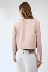 Chaqueta rosa de cuello solapa y manga larga, con cierre frontal y detalles de cremallera metálica.