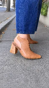 Zapatos abiertos en el talón modelo Eliana, con taco bloque de madera de 7,5 cm, punta fina y diseño lateral con abertura. Combinan diferentes texturas y tonos de cuero en color camel.