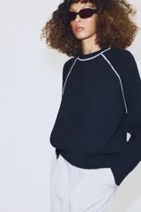 Jersey de punto de manga larga con cuello redondo, diseño en color azul marino con detalles de vivo en color blanco en el cuello y las costuras de las mangas.