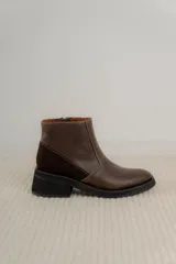 Bota corta de cuero marrón con panel trasero de gamuza en tono más oscuro, suela de goma negra y taco cuadrado bajo.