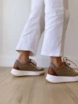 Championes de cuero color visón con cordones marrones, suela blanca y base color caramelo.