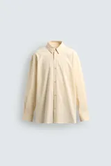 Camisa de corte regular fit confeccionada en tejido de algodón con textura de rayas verticales. Presenta cuello solapa, cierre frontal de botones y mangas largas con puños abotonados.