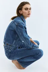 Jean de cinco bolsillos en denim de algodón con stretch. Modelo bootcut de tiro alto, ajustado de cintura a cadera y con corte ligeramente acampanado desde la rodilla hacia el bajo. Presenta raya marcada en la parte delantera y trasera.