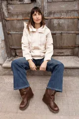 Gabardina liviana color beige con capucha, cierre frontal oculto y cintura ajustable mediante cordón. Presenta bolsillos delanteros amplios y mangas largas con puños rectos.