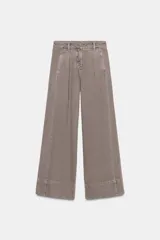 Jeans de tiro medio con corte wide leg y pinzas delanteras. Presenta bolsillos frontales, bolsillos de plastrón en la parte trasera y cierre frontal con cremallera, botón interior y ganchos metálicos.