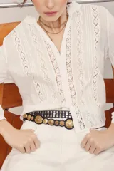 Camisa de manga larga blanca con detalles de encaje y entredos verticales, escote en V y cuello mao con volados sutiles.