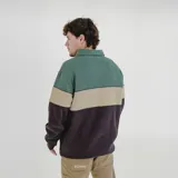 Buzo blanco con franja horizontal verde con la inscripción "Pulau" en blanco. Tiene cuello tipo polo con cierre de cremallera.