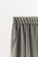 Pantalón palazzo gris de tejido semitransparente con tiro medio, cintura elástica, bolsillos laterales y forro interior corto.