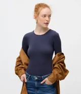 Body de manga larga con cuello redondo, confeccionado en tejido de poliamida y elastano sin costuras. Presenta un diseño ajustado al cuerpo con cierre inferior mediante botones de presión.