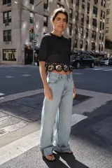Top de punto negro con cuello redondo y manga corta. Presenta un diseño de tejido calado en el bajo con aplicaciones estructurales en forma de flores en color beige.