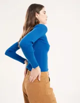 Polera negra de tejido de punto acanalado, con cuello alto y mangas largas.