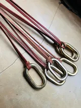 Collar con dije ovalado de bronce colgando de un tiento de cuero marrón.