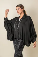 Camisa negra oversize de viscosa con cuello clásico, cierre frontal con botones y mangas largas abullonadas con puños fruncidos.