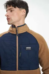 Buzo de hombre con cierre frontal, confeccionado en tejido sherpa color camel, con paneles superiores en verde oliva acolchado y cuello alto en color beige.