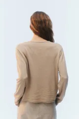 Cardigan de punto fino color beige, con escote en V, cierre frontal de botones y mangas largas.