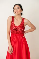 Vestido largo rojo con cuerpo de lentejuelas y falda de satén con caída fluida. Presenta escote redondo, sin mangas y un lazo en la cintura.