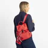 Mochila de nylon color rojo, con tapa frontal, broche metálico y cierre tipo marinero. Cuenta con bolsillo frontal con cierre metálico, bolsillos laterales, asas de mano y correas regulables para la espalda.