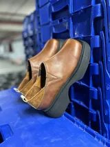 Zapato marrón de cuero con elástico en los laterales y suela de goma negra.