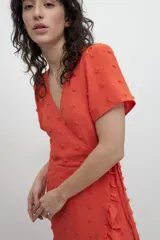 Vestido corto color naranja con estampado de lunares en relieve, escote en V cruzado, mangas cortas y volantes en el ruedo.