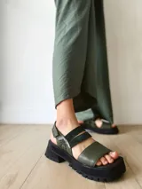 Sandalia de cuero verde con ajuste de velcro y suela track.