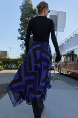 Falda midi de corte asimétrico con diseño cruzado en el delantero y aberturas. Presenta un estampado geométrico en tonos azul, negro y beige, con forro interior y cierre trasero con cremallera oculta.