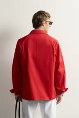 Sobrecamisa de algodón de corte relajado, color negro con efecto gastado, cuello con solapas de muesca, mangas largas raglán y cierre frontal con botones. Cuenta con bolsillos frontales de plastrón en el pecho y en la parte inferior.