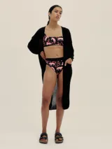 Cárdigan largo tejido en jersey color negro, con bolsillos delanteros y detalle de logo en cobre.