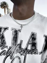 Collar de perlas blancas con dije de cruz plateada con incrustaciones de strass.