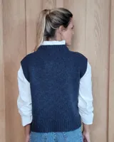 Chaleco de punto gris oscuro con diseño de trenzas y rombos en relieve, cuello redondo y terminaciones acanaladas.