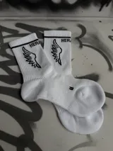 Par de medias blancas de algodón con puño acanalado con una línea negra, logo de la marca en el tobillo y estampado de alas negras.