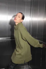 Sweater verde oliva de tejido de punto con cuello polo, mangas largas y corte oversize. Presenta un parche con monograma en la espalda.