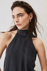Blusa crop azul oscuro con cuello alto y diseño sin mangas, de tela con caída suave y ligero brillo.