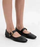 Zapatilla tipo bailarina Satinato de cuero negro, con punta cuadrada, tacón bajo y tira en el empeine con hebilla metálica dorada grande.