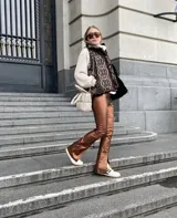 Chaleco marrón con estampado abstracto en tonos marrones y negros, con cierre frontal y broches a presión. Interior forrado con tela de peluche color crema y bolsillo interno.