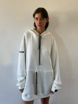 Vestido tipo hoodie oversize de tejido waffle, color crudo, con capucha y cordones ajustables en contraste. Presenta un cordón interno en la cintura para entallar la prenda y bolsillos laterales.