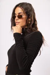 Polera negra de manga larga con cuello alto y detalle de drapeado en las mangas. Confeccionada en tela stretch suave con leve brillo.