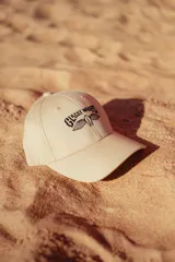 Gorra color crudo con logo bordado en negro en el frente.