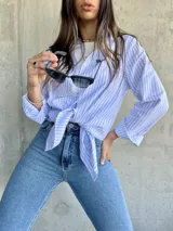 Camisa de manga larga con rayas verticales celestes y blancas, de corte recto y largo con aberturas laterales.