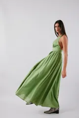 Vestido midi de color verde, con escote en V profundo, banda ancha bajo el busto y falda amplia con gran volumen. Presenta espalda baja y cierre invisible.