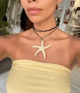 Collar con tiento encerado negro y dije grande con forma de estrella de mar de color hueso o beige claro.